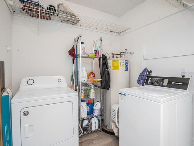 laundry room with laundry area, water heater, separate washer and dryer, and wood finished floors