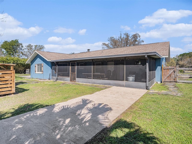 back of property with a sunroom, a gate, fence, and a lawn