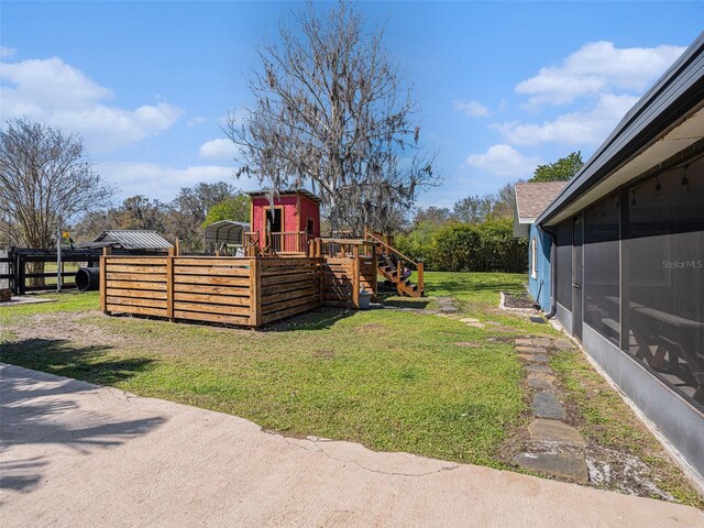 view of yard with a playground, fence, and a sunroom