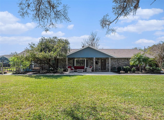 back of house featuring a yard, stone siding, a patio, and a shingled roof