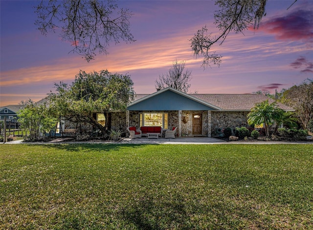 view of front facade featuring stone siding, a patio area, an outdoor living space, and a front yard