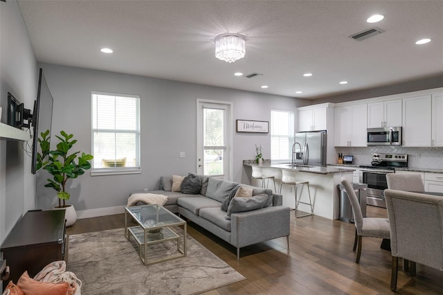 living area with dark wood-style floors, baseboards, visible vents, and recessed lighting