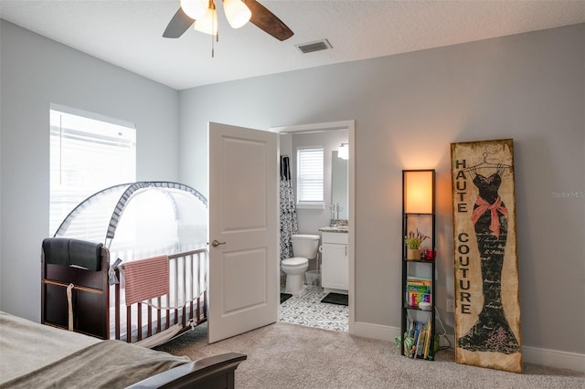 carpeted bedroom with ensuite bath, visible vents, and baseboards