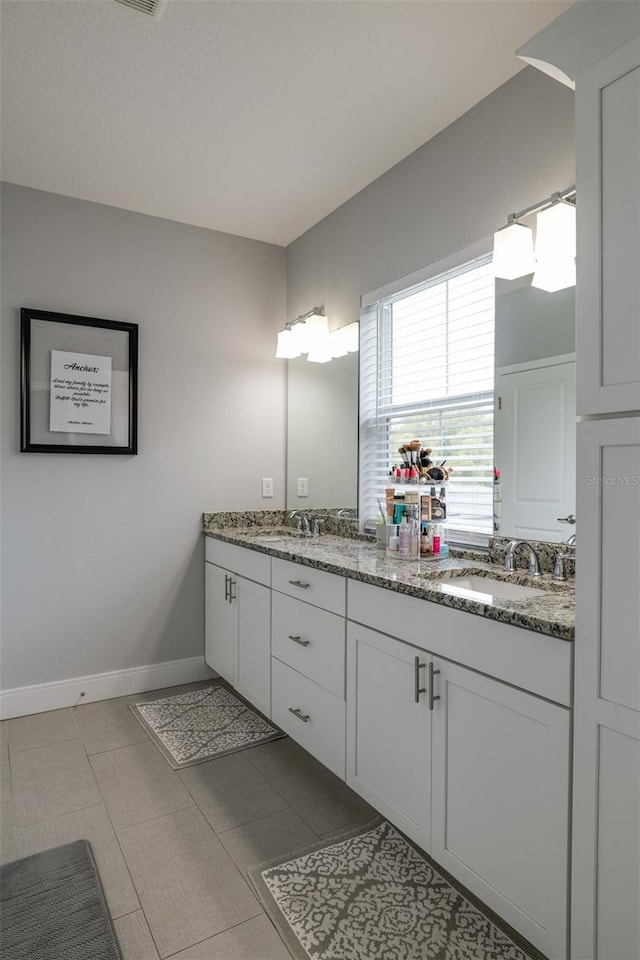 bathroom with double vanity, a sink, and baseboards