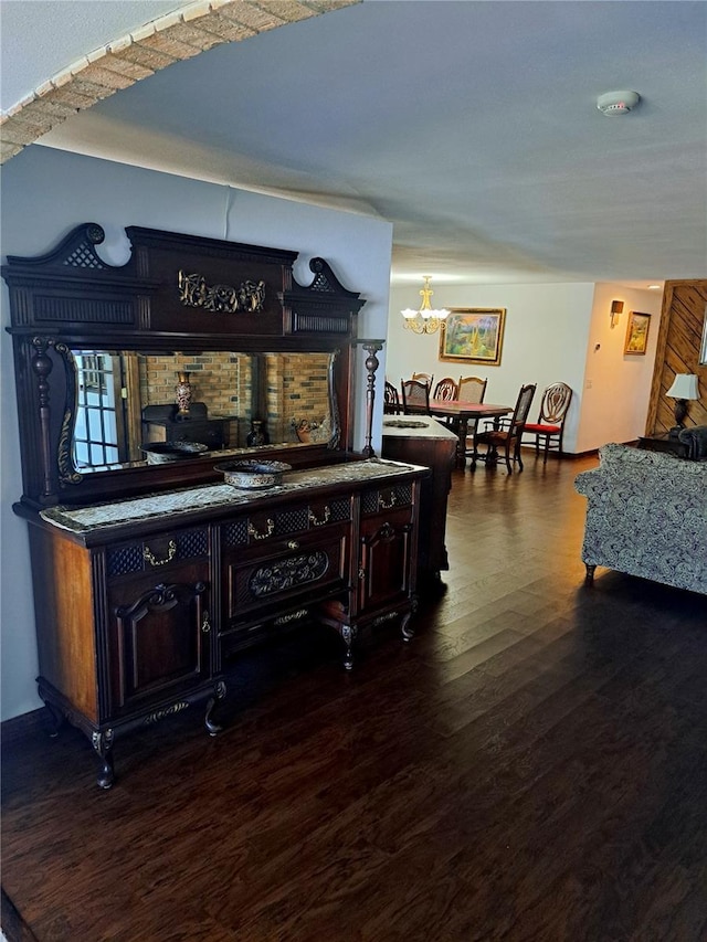 bar featuring dark wood-style floors and an inviting chandelier