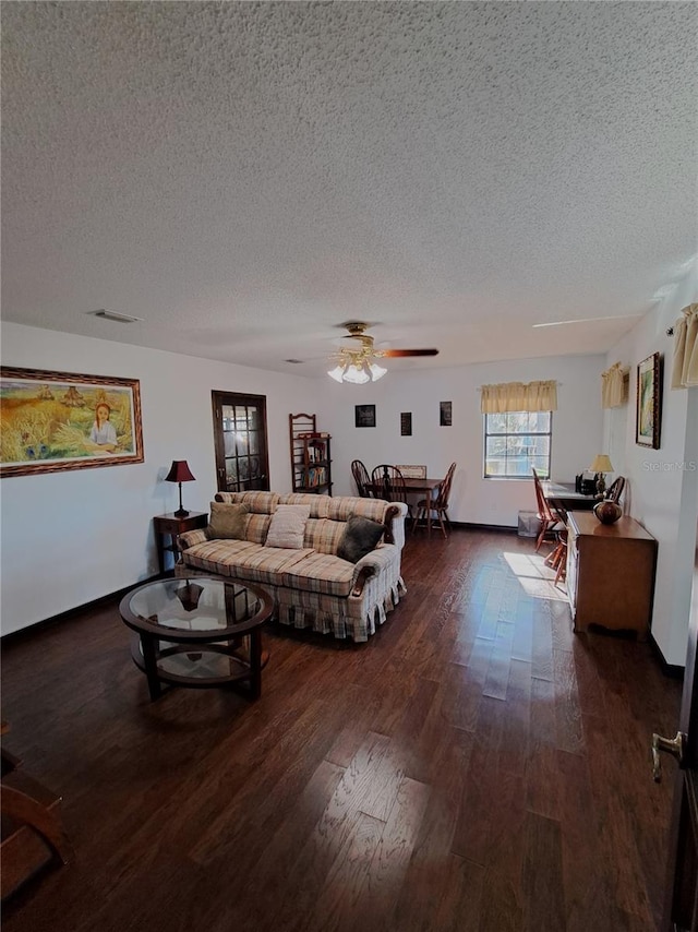 living room with ceiling fan, a textured ceiling, wood finished floors, and visible vents