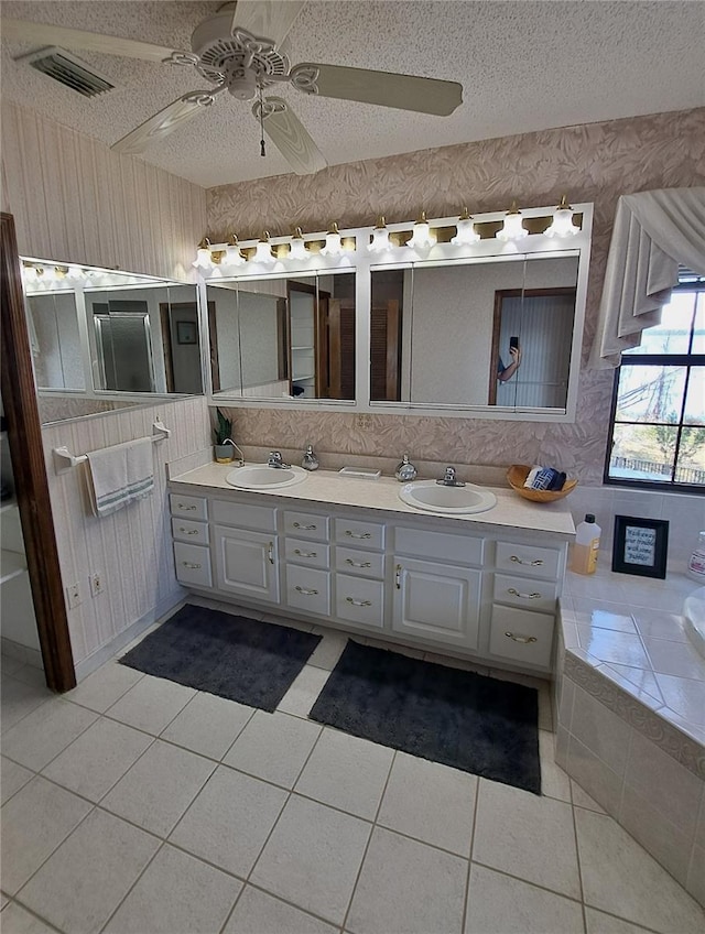 bathroom featuring a textured ceiling, double vanity, a sink, and visible vents