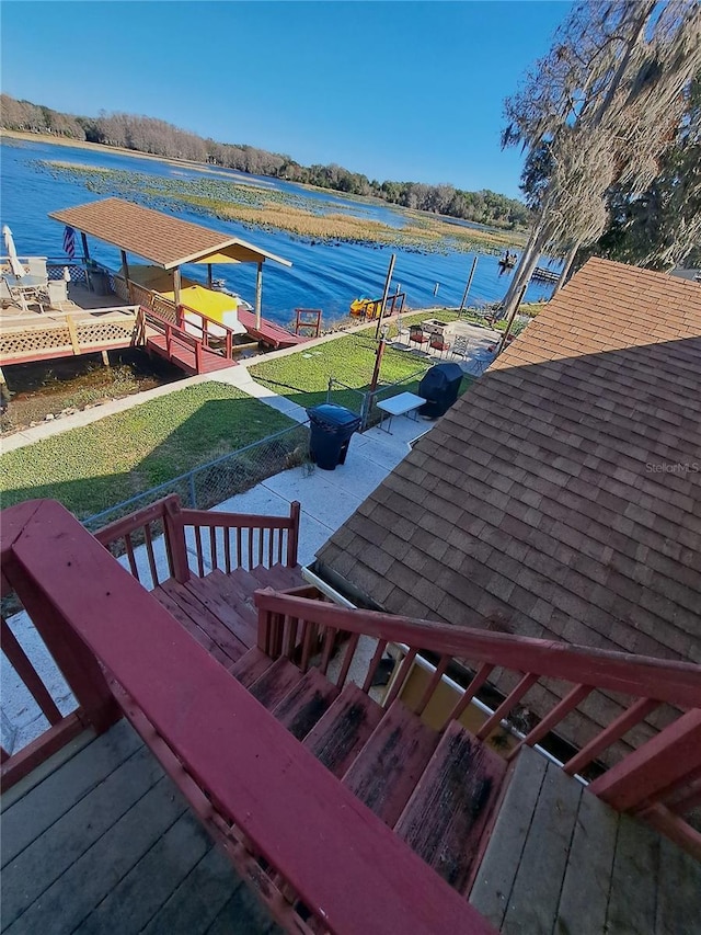 exterior space featuring a dock, a water view, and a lawn