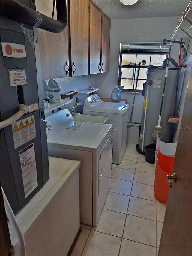 clothes washing area featuring washer and clothes dryer, light tile patterned floors, water heater, cabinet space, and a textured ceiling