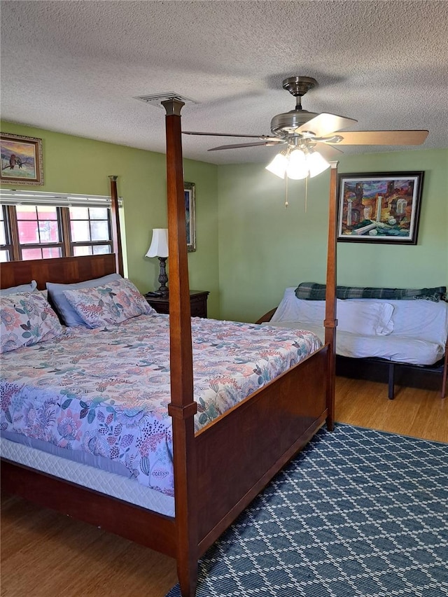 bedroom with ceiling fan, a textured ceiling, and wood finished floors