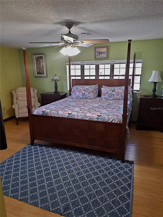 bedroom featuring a textured ceiling, multiple windows, and wood finished floors