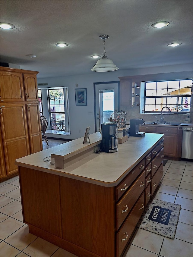 kitchen with dishwasher, light countertops, a kitchen island, and a sink