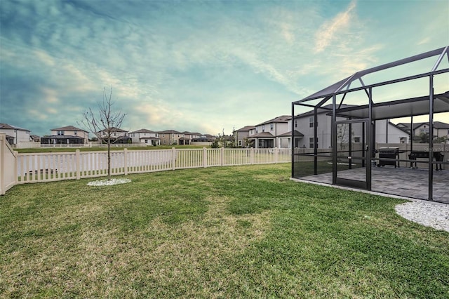 view of yard with glass enclosure, a patio area, a fenced backyard, and a residential view