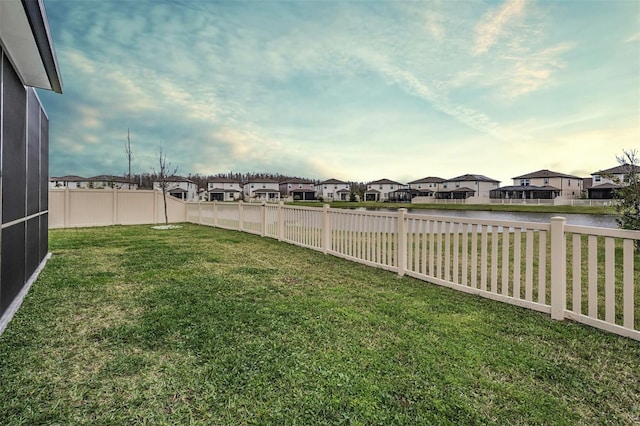 view of yard with a water view, a fenced backyard, and a residential view