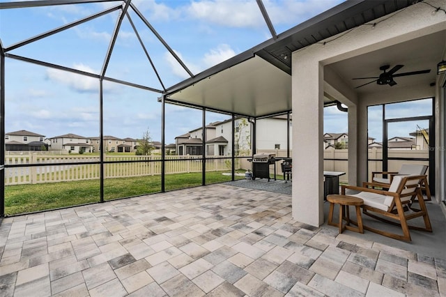 view of patio featuring ceiling fan, glass enclosure, outdoor dining area, fence, and a residential view