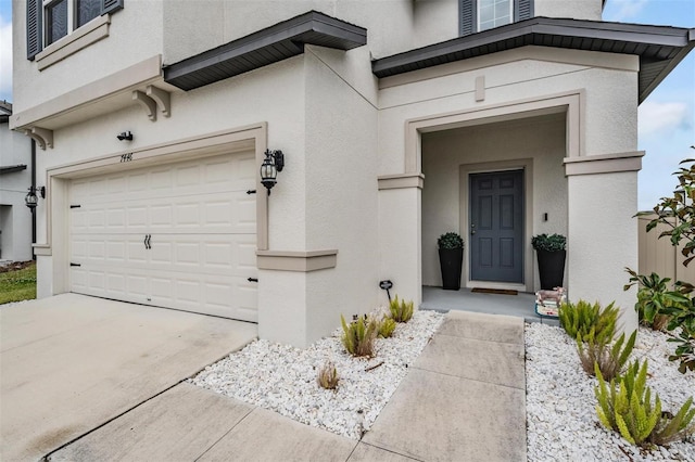 doorway to property with a garage, concrete driveway, and stucco siding