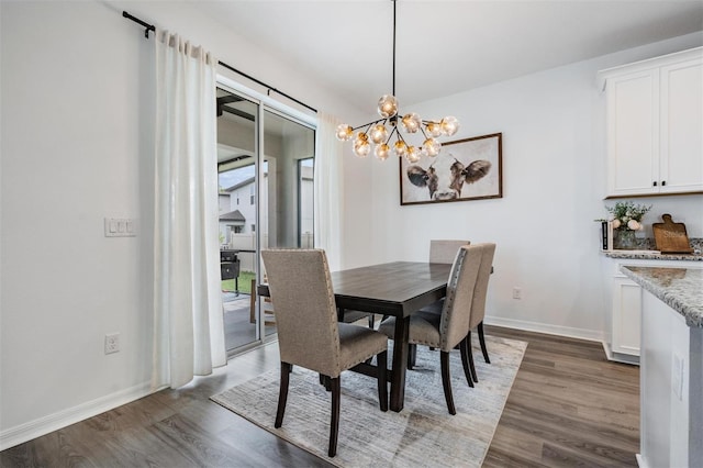 dining room featuring a notable chandelier, baseboards, and wood finished floors