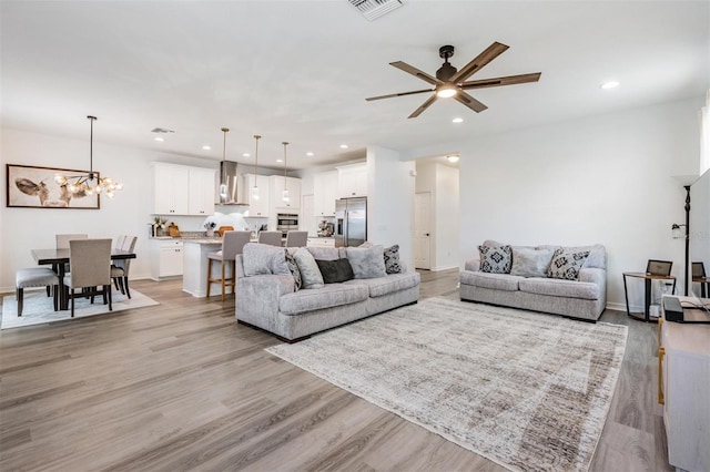 living room featuring light wood-type flooring, visible vents, baseboards, and recessed lighting