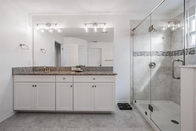 bathroom with a sink, a shower stall, baseboards, and double vanity