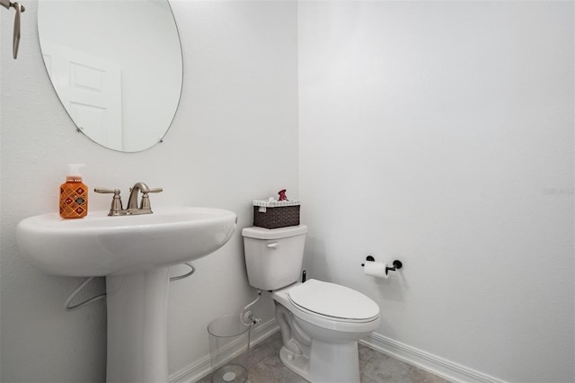 half bath featuring toilet, baseboards, and a sink