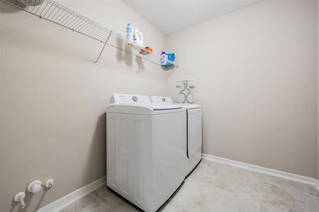 clothes washing area with laundry area, separate washer and dryer, and baseboards