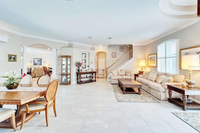 living room with light tile patterned floors, decorative columns, arched walkways, ornamental molding, and stairs