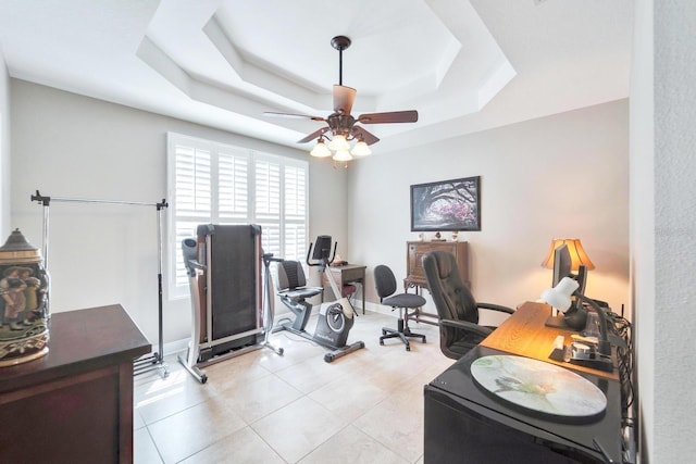 office area with light tile patterned floors, baseboards, a tray ceiling, and a ceiling fan