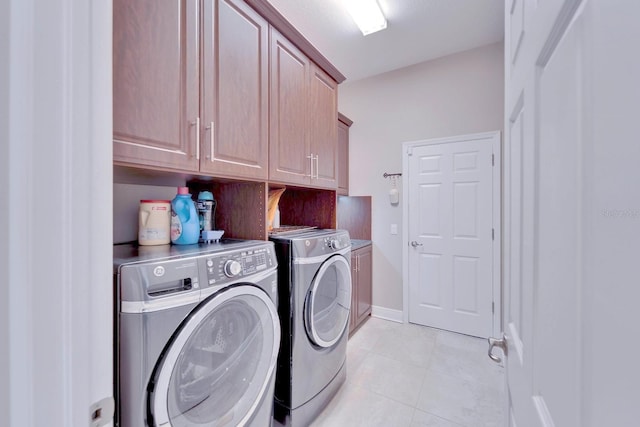 laundry room with light tile patterned floors, washing machine and dryer, cabinet space, and baseboards