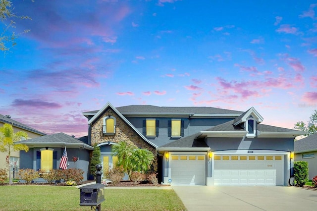 traditional-style house featuring driveway, a garage, a front yard, and stucco siding