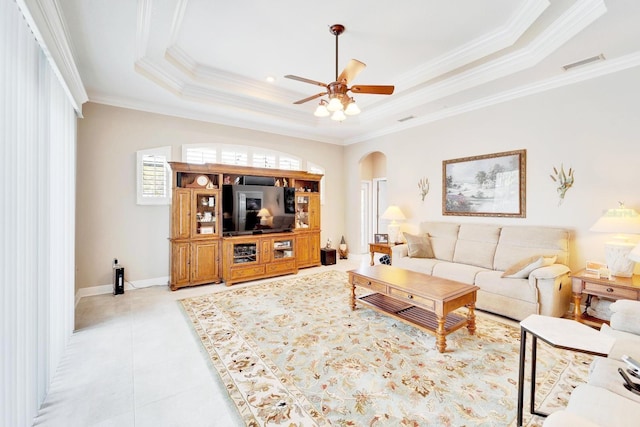 living area featuring visible vents, arched walkways, ornamental molding, a tray ceiling, and light tile patterned flooring