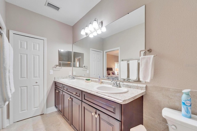 ensuite bathroom featuring visible vents, a sink, toilet, and double vanity