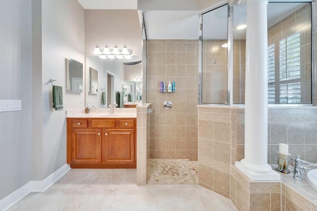 bathroom with vanity, baseboards, a bath, walk in shower, and decorative columns