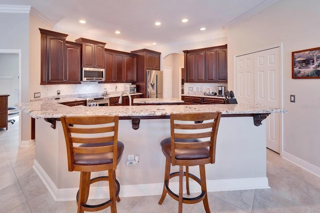 5115 Abisher Wood Ln, Brandon, FL 33511 - kitchen with appliances with stainless steel finishes, arched walkways, a kitchen bar, backsplash, and crown molding