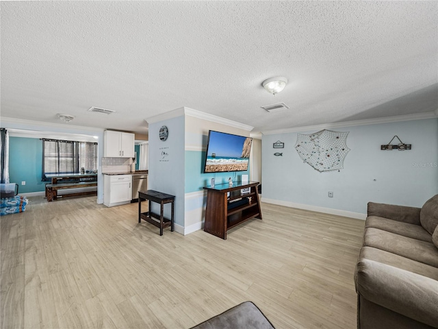 living room featuring ornamental molding, light wood finished floors, a textured ceiling, and visible vents