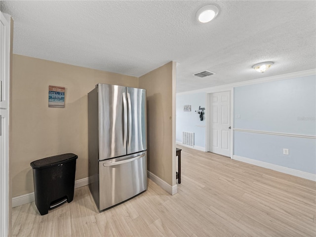 kitchen with light wood-style floors, baseboards, visible vents, and freestanding refrigerator