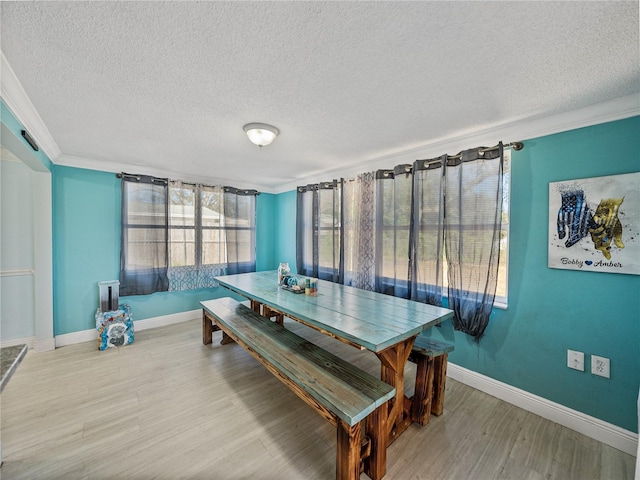 dining room with crown molding, a textured ceiling, baseboards, and wood finished floors