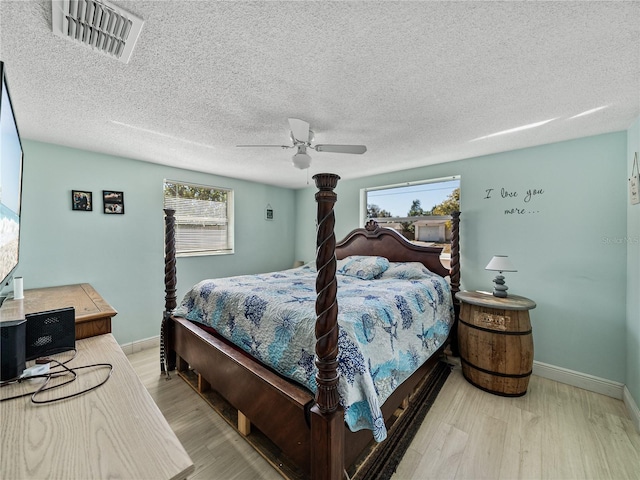 bedroom featuring a ceiling fan, wood finished floors, visible vents, and multiple windows