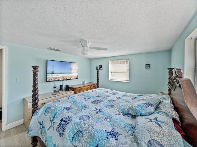 bedroom with baseboards, visible vents, a ceiling fan, wood finished floors, and a textured ceiling