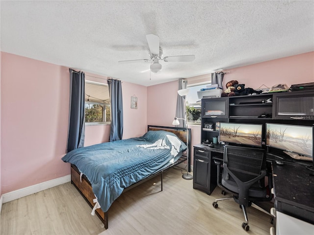 bedroom with a textured ceiling, ceiling fan, light wood-type flooring, and baseboards