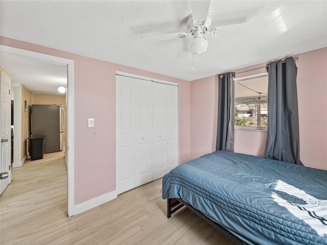 bedroom featuring baseboards, a ceiling fan, a textured ceiling, light wood-style floors, and a closet