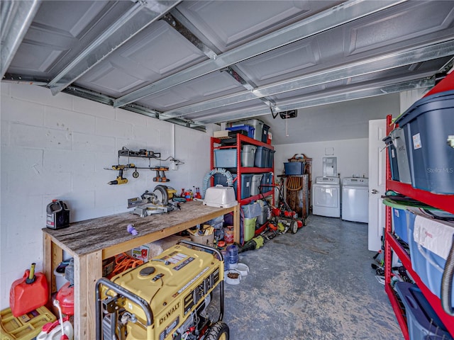 garage featuring concrete block wall, separate washer and dryer, and a workshop area