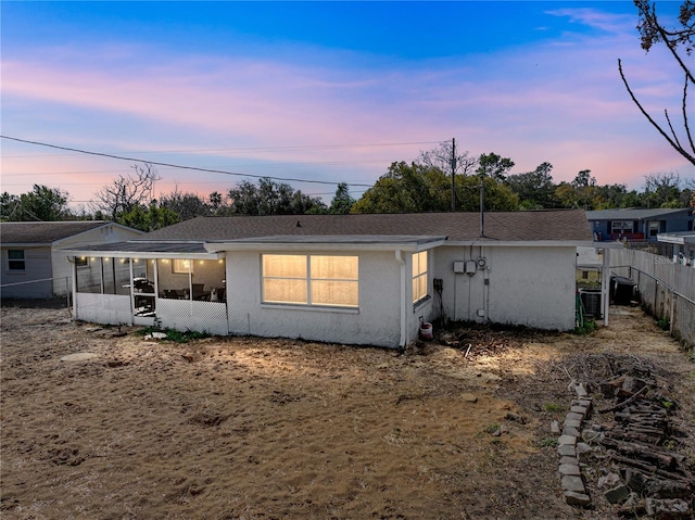 rear view of property with fence, a sunroom, and stucco siding