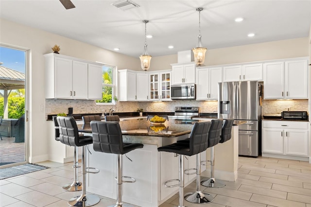 kitchen with stainless steel appliances, a kitchen island, visible vents, and white cabinets