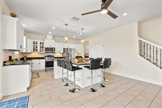 kitchen with dark countertops, visible vents, decorative backsplash, appliances with stainless steel finishes, and a sink