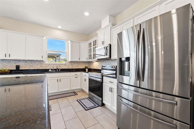 kitchen featuring appliances with stainless steel finishes, light tile patterned flooring, white cabinetry, and tasteful backsplash