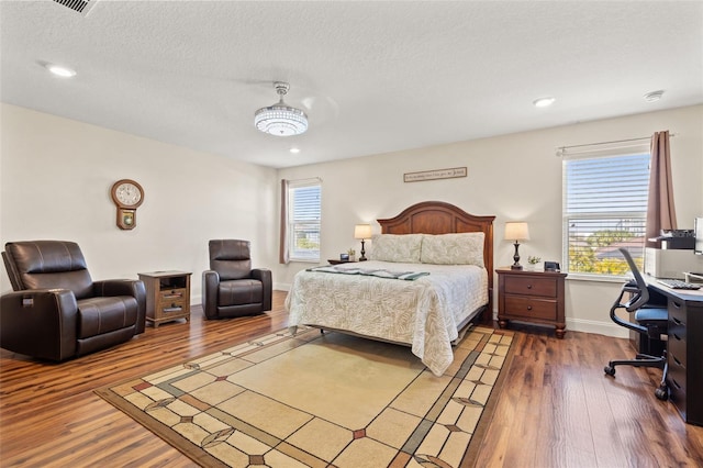 bedroom with a textured ceiling, multiple windows, and wood finished floors