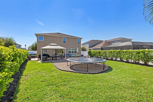 rear view of property with fence, a gazebo, a yard, a trampoline, and a patio area