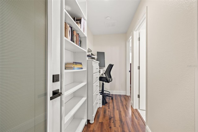 hall featuring dark wood-style flooring, visible vents, and baseboards