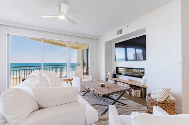 living room featuring a healthy amount of sunlight, ceiling fan, visible vents, and wood finished floors