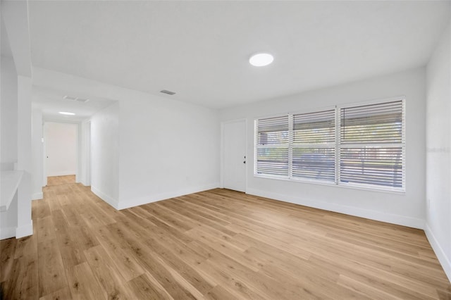 spare room featuring light wood finished floors, visible vents, and baseboards